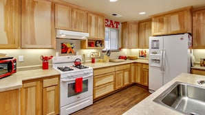 A kitchen with wooden cabinets, a stove, a microwave, and a refrigerator. - Idle Hours ~ Fantastic River Views & Walk to Downtown! Classic Russian River! (Guerneville)