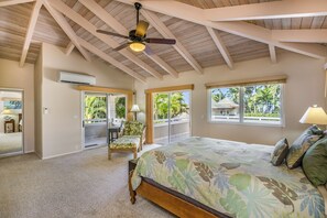 Une chambre à coucher avec un lit, un ventilateur de plafond et de grandes fenêtres.