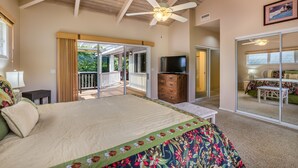 A spacious bedroom with a large bed, a ceiling fan, a TV, and a sliding glass door leading to a balcony. - LAST MINUTE DISCOUNT SPECIAL! Central A/C Double Master Suite Home. (Kailua-Kona)