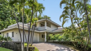 A two-story house with a garage, surrounded by palm trees and a stone wall. - LAST MINUTE DISCOUNT SPECIAL! Central A/C Double Master Suite Home. (Kailua-Kona)