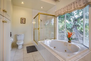 A bathroom with a glass-enclosed shower, a white toilet, and a large bathtub with a window view. - LAST MINUTE DISCOUNT SPECIAL! Central A/C Double Master Suite Home. (Kailua-Kona)