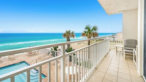 Un balcon avec piscine, vue sur la plage et espace salon extérieur.