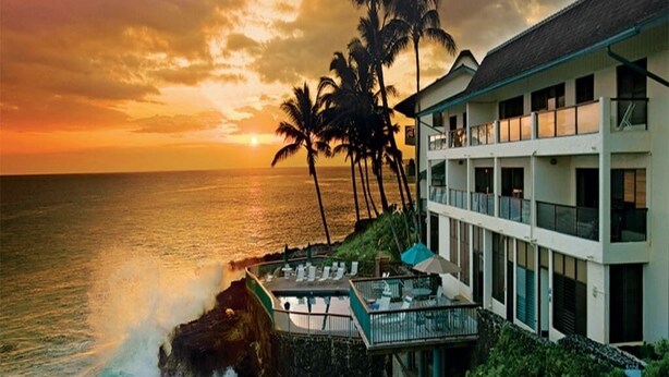Ein Hotel am Strand mit Pool, Palmen und Meerblick.