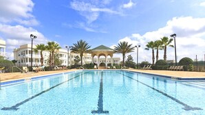 A swimming pool with a clear blue water, surrounded by lounge chairs and palm trees. - Beautifully Furnished Luxury Condo! Amazing Value near Disney (Kissimmee)