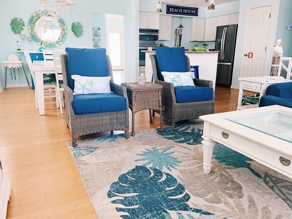 A living room with two wicker chairs, a glass coffee table, and a blue sofa. - Tides Inn- Family home with tropical pool area. (Anna Maria)