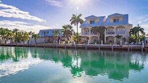 Propiedad frente al agua con una casa grande, varios balcones y un área de piscina.
