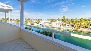 Un balcón con vista a una piscina y palmeras.