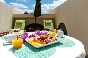 A breakfast setup with a plate of fruits, muffins, and a glass of orange juice on a table with a green placemat.