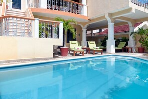 Une piscine avec des chaises longues et des plantes en pot.
