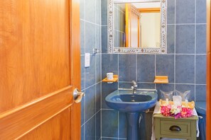 Une salle de bain avec une porte en bois, un lavabo bleu et un miroir doté d’un cadre décoratif.