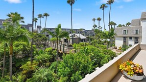 Un hôtel doté d’un jardin sur le toit, de palmiers et d’un balcon agrémenté de plantes en pot.