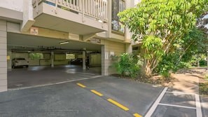 A parking garage entrance with a speed limit sign, a tow-away sign, and a warning sign about 24-hour surveillance.