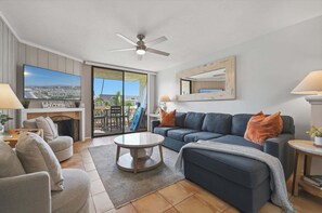 A modern living room with a sofa, armchairs, a coffee table, and a ceiling fan.