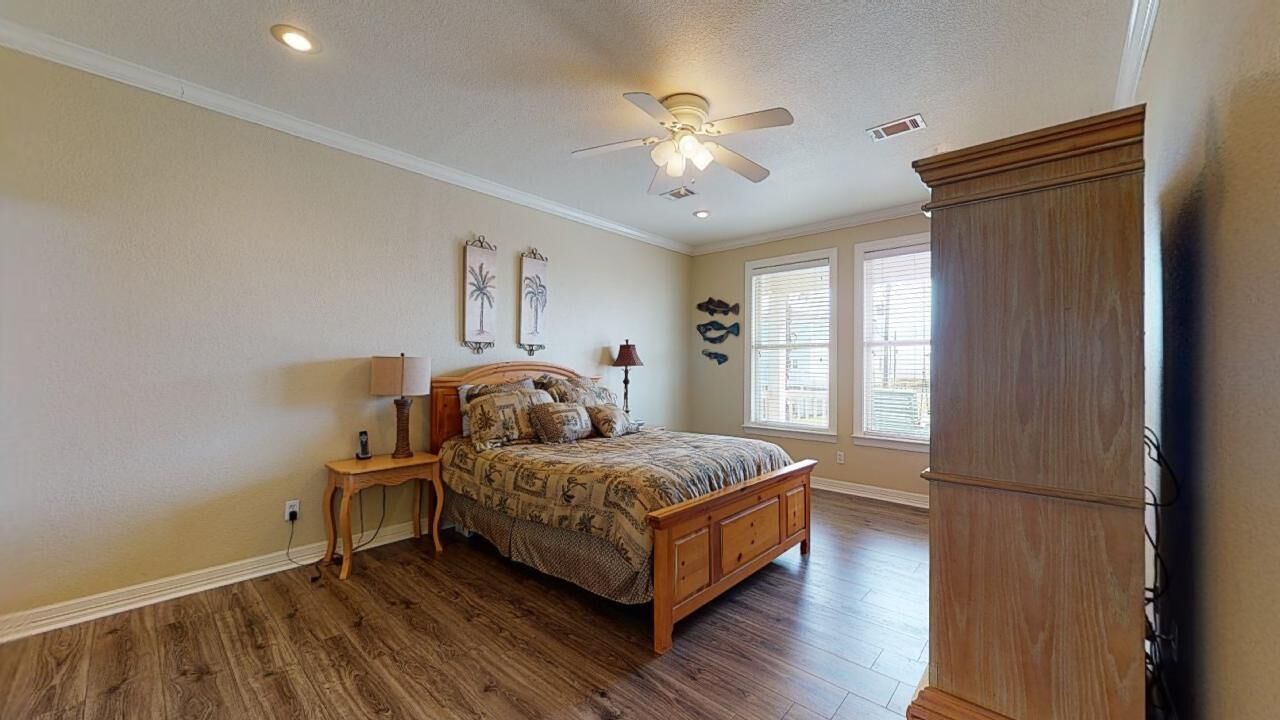 A bedroom with a wooden bed, a nightstand, a ceiling fan, and a large wardrobe.