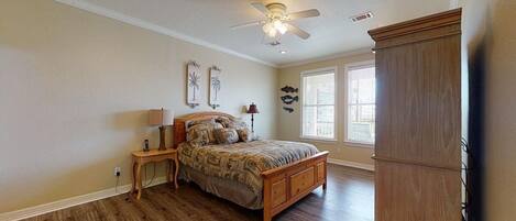 A bedroom with a wooden bed, a nightstand, a ceiling fan, and a large wardrobe.