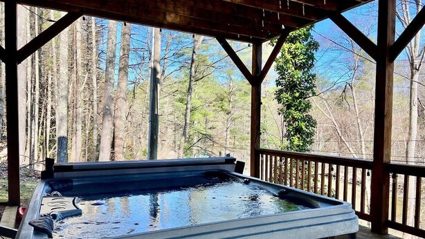 Ein Whirlpool auf einer Holzterrasse mit Blick auf einen Wald.