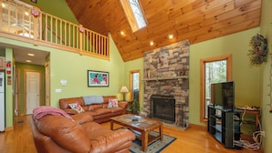 A spacious living room with a fireplace, wooden ceiling, and a television. - Peaceful Dog Friendly Escape w/ Dock & Fire Pit (Swanton)