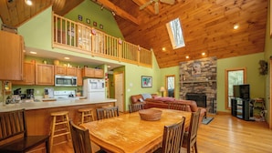A spacious kitchen with wooden cabinets, a central island, and a dining area with a large wooden table and chairs. - Peaceful Dog Friendly Escape w/ Dock & Fire Pit (Swanton)