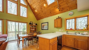 A spacious kitchen with wooden cabinets, a large island, and a dining area with chairs and a table. - Peaceful Dog Friendly Escape w/ Dock & Fire Pit (Swanton)