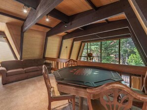 Una habitación acogedora con techo de madera, una mesa redonda con sillas y un sofá.