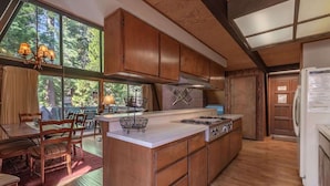 A kitchen with wooden cabinets, a large island, and a dining area with a table and chairs. - Unique 3 Story with Two Great Entertainment Areas! Short drive to Lake and Northstar! (Kings Beach)