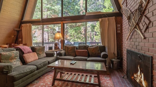 A cozy interior with a large window, a fireplace, and a sectional sofa. - Unique 3 Story with Two Great Entertainment Areas! Short drive to Lake and Northstar! (Kings Beach)
