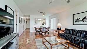 Uma sala de estar com sofá, mesa de centro e canto de jantar com cadeiras e mesa.