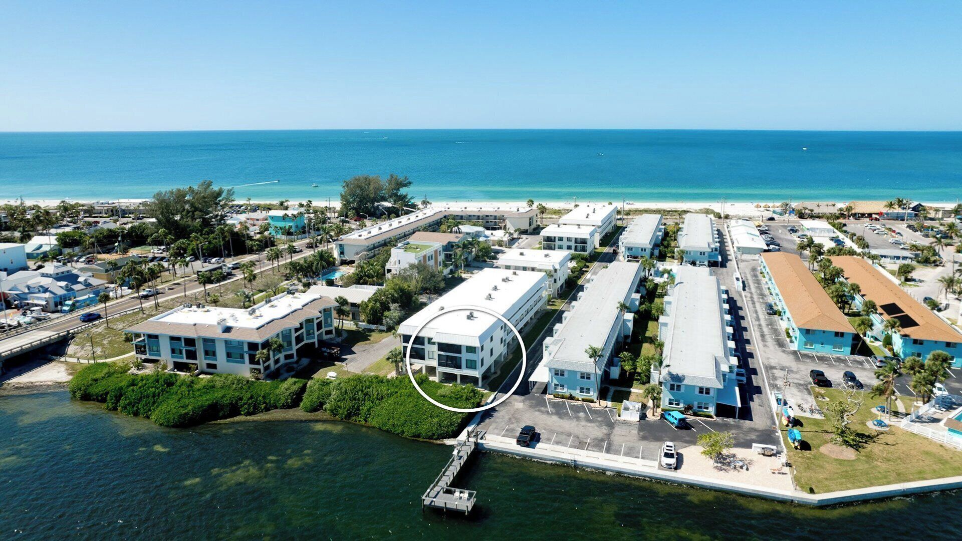 Eine Luftaufnahme eines Küstenhotels mit mehreren Gebäuden, einer Marina und einem Strand im Hintergrund.
