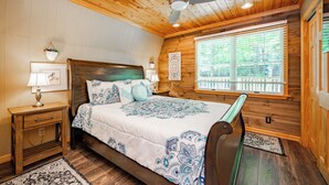 A wooden bedroom with a bed, nightstands, a ceiling fan, and a window with blinds. - Dog Friendly Getaway Just Steps to Wisp & Fun (MCHENRY)