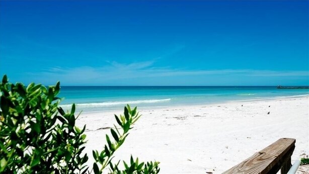 A beach with white sand and clear blue water.