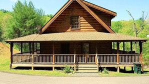 A log cabin with a porch and a triangular roof.