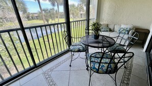 Ein Balkon mit Seeblick, ein Esstisch mit Stühlen sowie eine Couch mit Kissen.