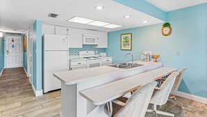A modern kitchen with white appliances, a central island, and a blue accent wall.