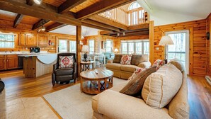 A log cabin interior with a dining area, kitchen, and living room furnished with leather sofas and a coffee table. - Tranquil Dog Friendly Escape w/ Dock Slip (Oakland)