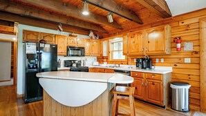 A kitchen with wooden cabinets, a refrigerator, a microwave, and a sink. - Tranquil Dog Friendly Escape w/ Dock Slip (Oakland)