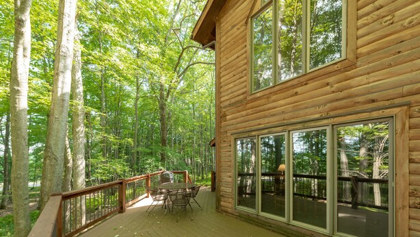 A wooden cabin with a deck, large windows, and a dining area. - Tranquil Dog Friendly Escape w/ Dock Slip (Oakland)