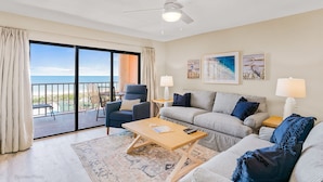 A spacious living room with a balcony, a ceiling fan, a sofa set, and a coffee table. - Gulf Front BEACH getaway - Reef Club 308 (Indian Rocks Beach)