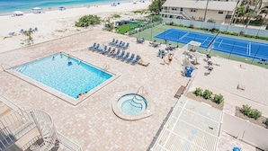 A pool area with a large pool, a smaller hot tub, and a tennis court. - Gulf Front BEACH getaway - Reef Club 308 (Indian Rocks Beach)