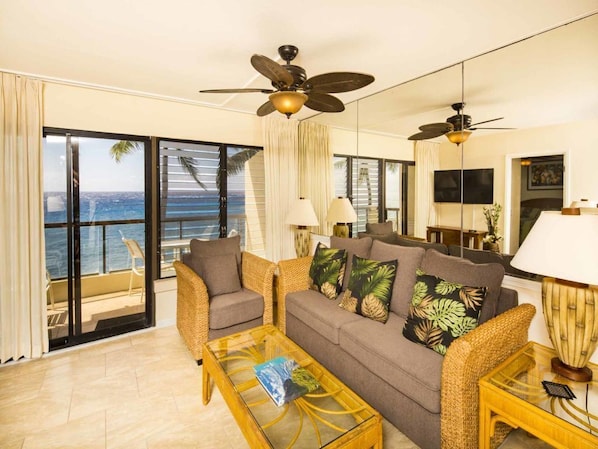 A living room with a sofa, chairs, a coffee table, and a ceiling fan.
