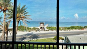 A view of a coastal road with a lifeguard tower, palm trees, and a clear sky.