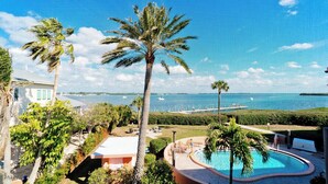 A resort with a pool, palm trees, and a view of the ocean.