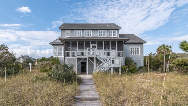 A two-story house with a porch and a staircase leading to the entrance. - Timeless Oceanfront Beach Retreat in DeBordieu (Georgetown)
