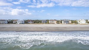 A beachfront property with multiple houses, a sandy beach, and waves in the foreground. - Timeless Oceanfront Beach Retreat in DeBordieu (Georgetown)