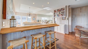 A spacious kitchen with a wooden bar, bar stools, and a large island. - Timeless Oceanfront Beach Retreat in DeBordieu (Georgetown)