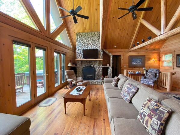 Cozy living area with a stone fireplace, comfortable seating, and large windows offering views of the surrounding landscape.