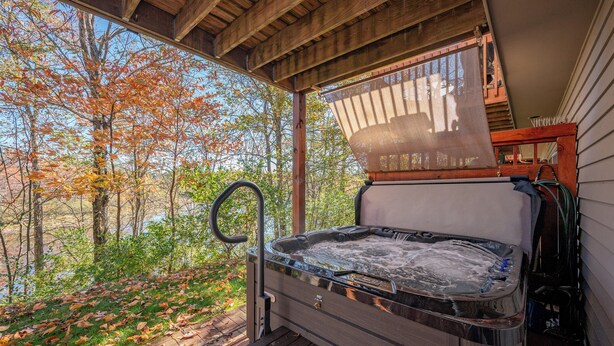 Un jacuzzi con cubierta de madera y vistas a árboles otoñales.