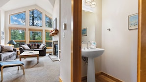 Ein geräumiges Wohnzimmer mit Kamin, großen Fenstern und Blick auf Bäume.