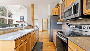 Eine moderne Küche mit Holzausstattung, Edelstahlgeräten und einem großen Fenster für viel natürliches Licht.