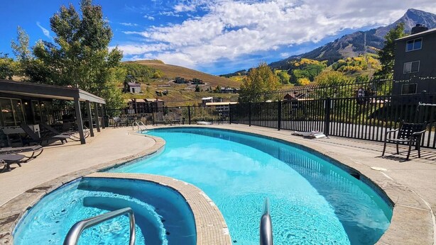 A swimming pool with a curved design, surrounded by a stone deck and metal railings.