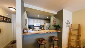 A kitchen with a wooden countertop, two stools, and a ladder.